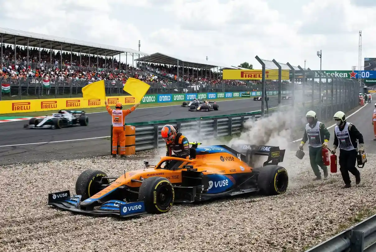 Monoplaza F1 detenido en la grava con humo saliendo del motor